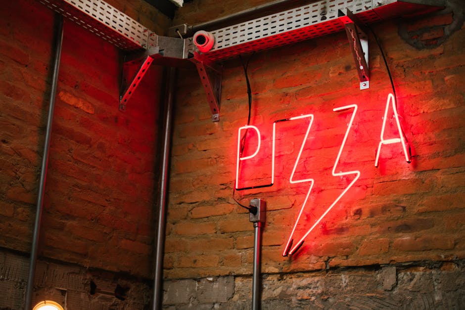 A striking neon pizza sign illuminates a rustic brick wall, adding charm.